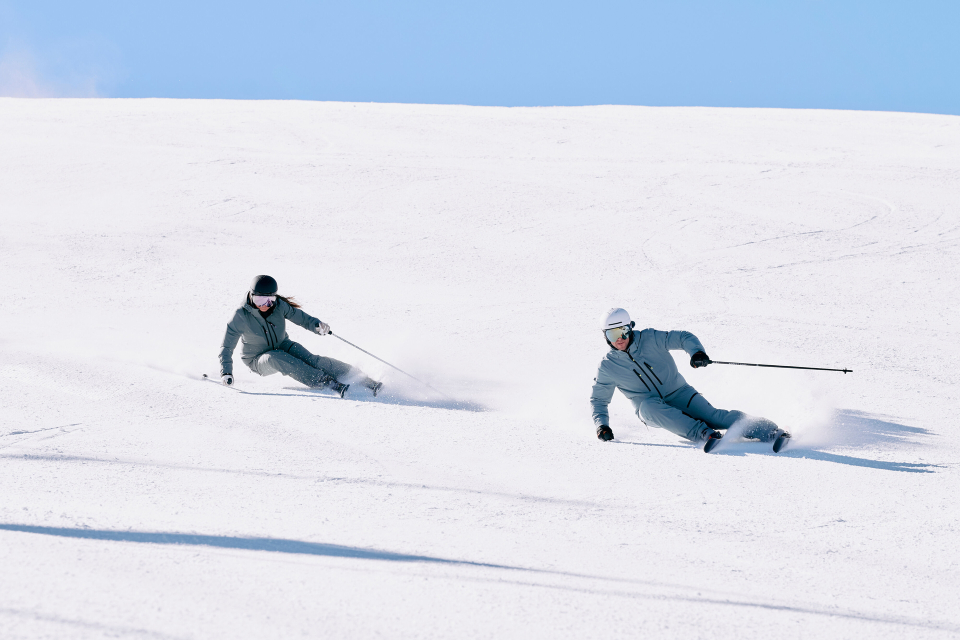 Zwei Skifahrer carven die Piste runter