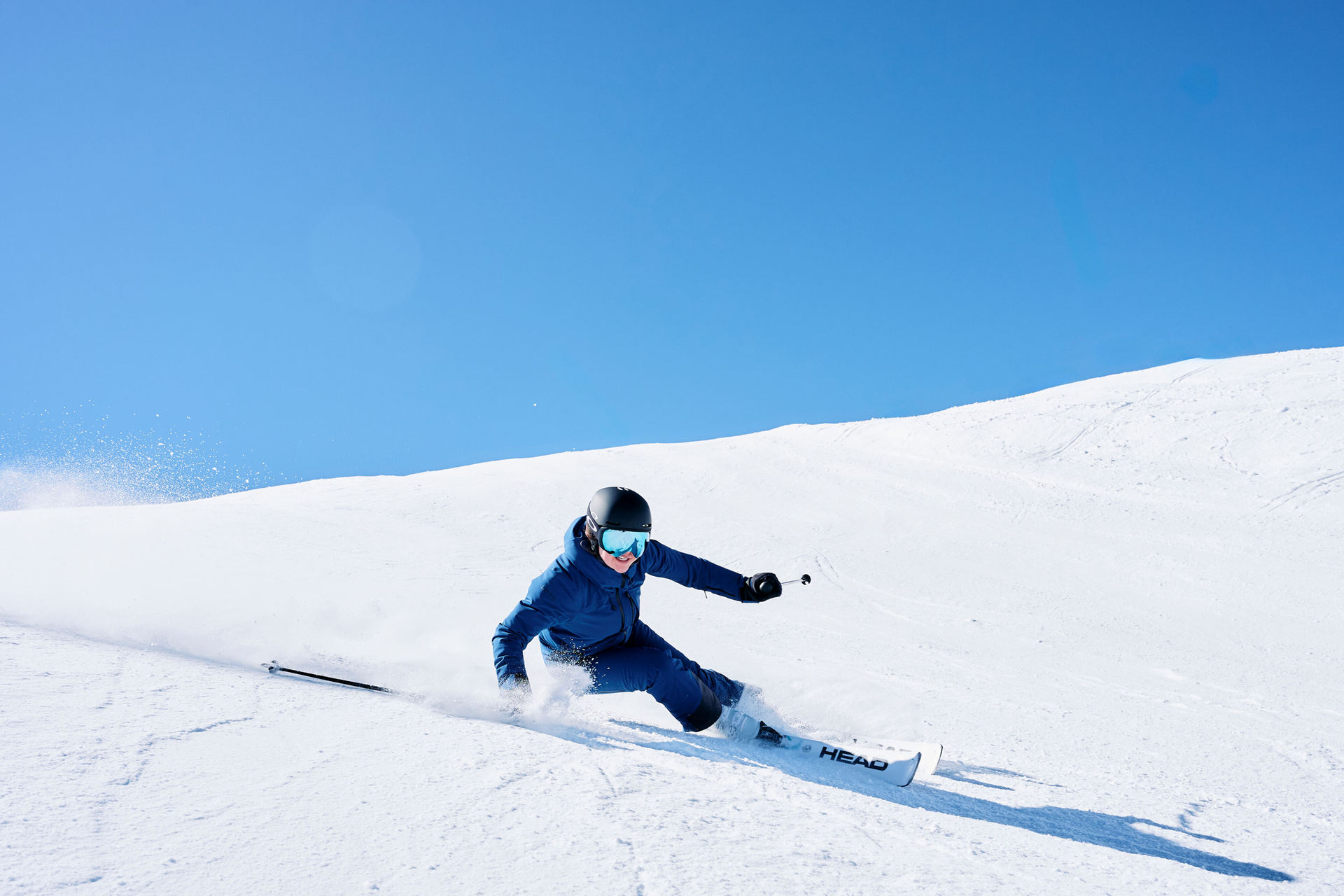 Skifahrer in blauer Kleidung fährt die Piste runter
